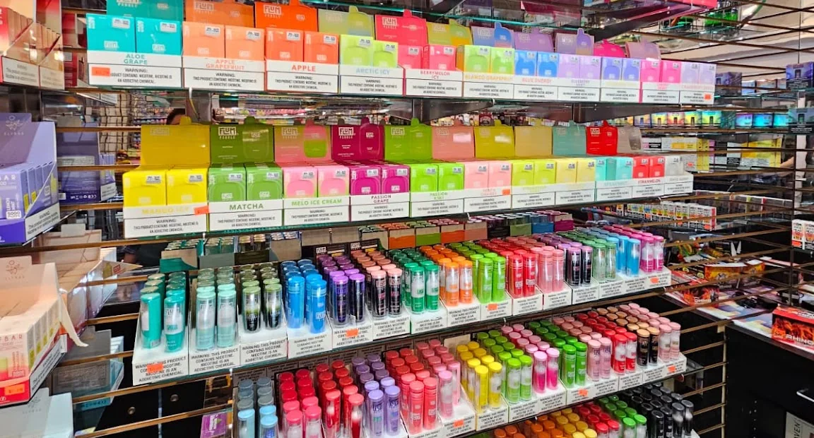 The vape wall at Puff Vegas: rows of disposables sorted by flavour, every colour of the spectrum, with lighters on the shelf below.
